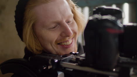 close up view of a redhead cameraman recording a scene in a ruined building