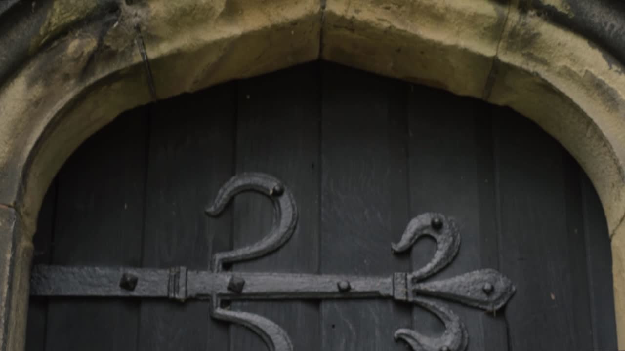 Gothic looking old black wooden door in stone church building
