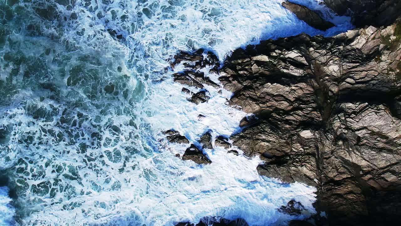Onde bianche dell'oceano al rallentatore sulle rocce della Cornovaglia, Regno Unito.