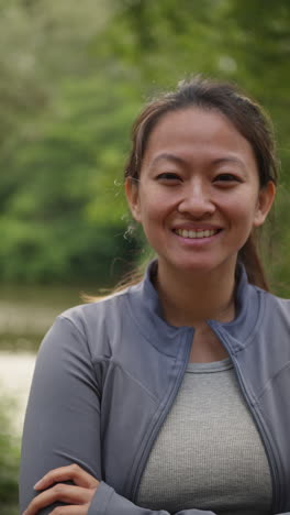 Vertical-Video-Portrait-Of-Smiling-Mid-Adult-Woman-Exercising-Doing-Work-Out-Outdoors-In-Forest-Wearing-Sports-Clothing-Shot-In-Real-Time