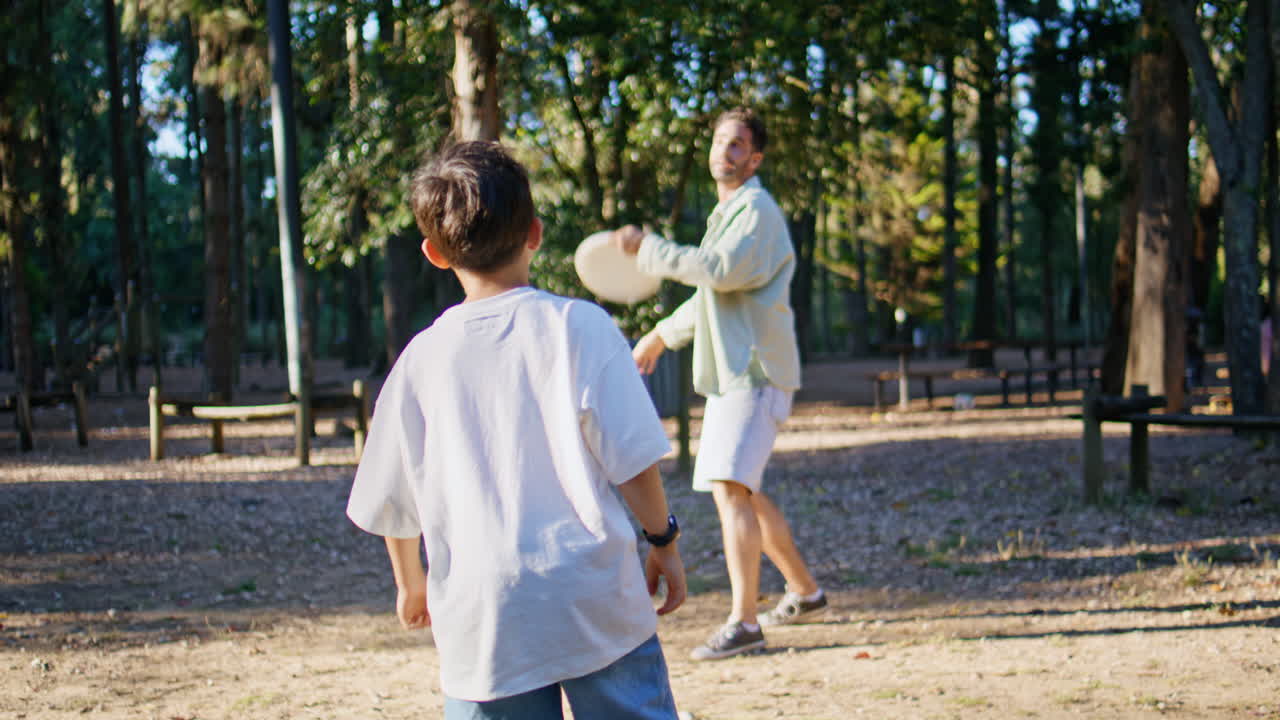Carefree family playing game having fun in sunbeams park. Man throwing frisbee