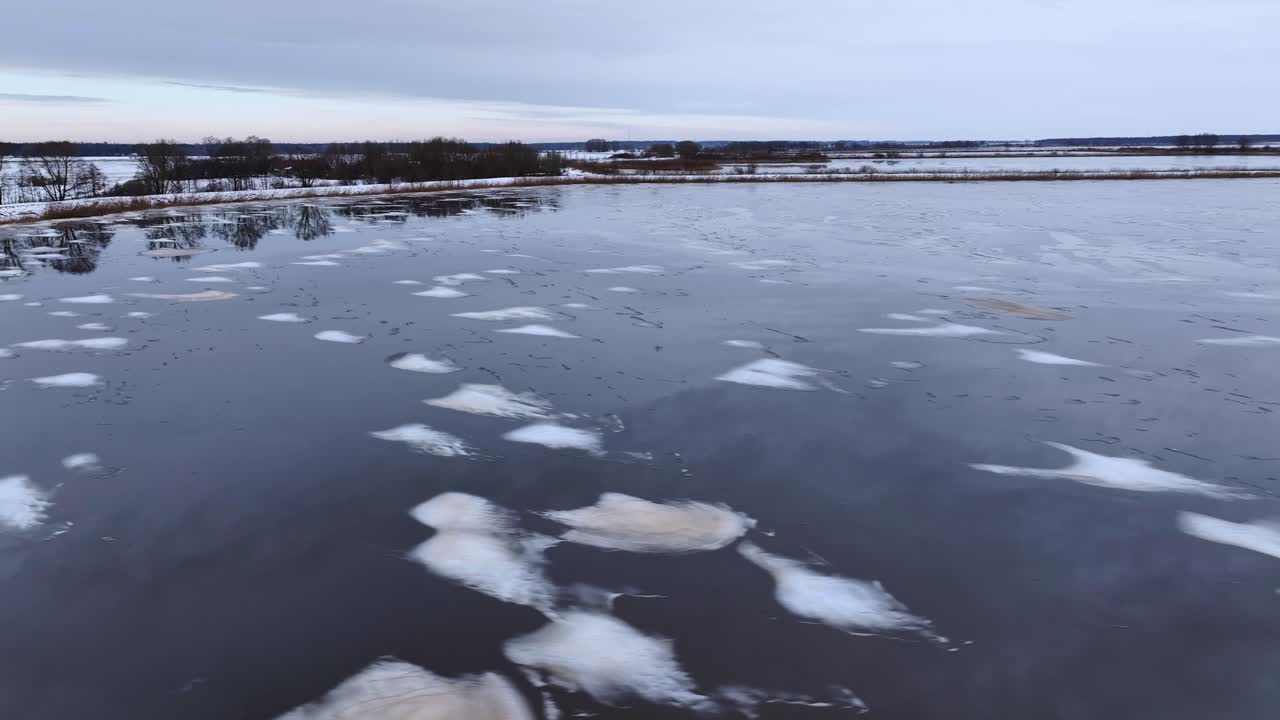 An aerial view of small ice chunks and mud spots floating on the water surface in wintertime. Europe Lithuania.