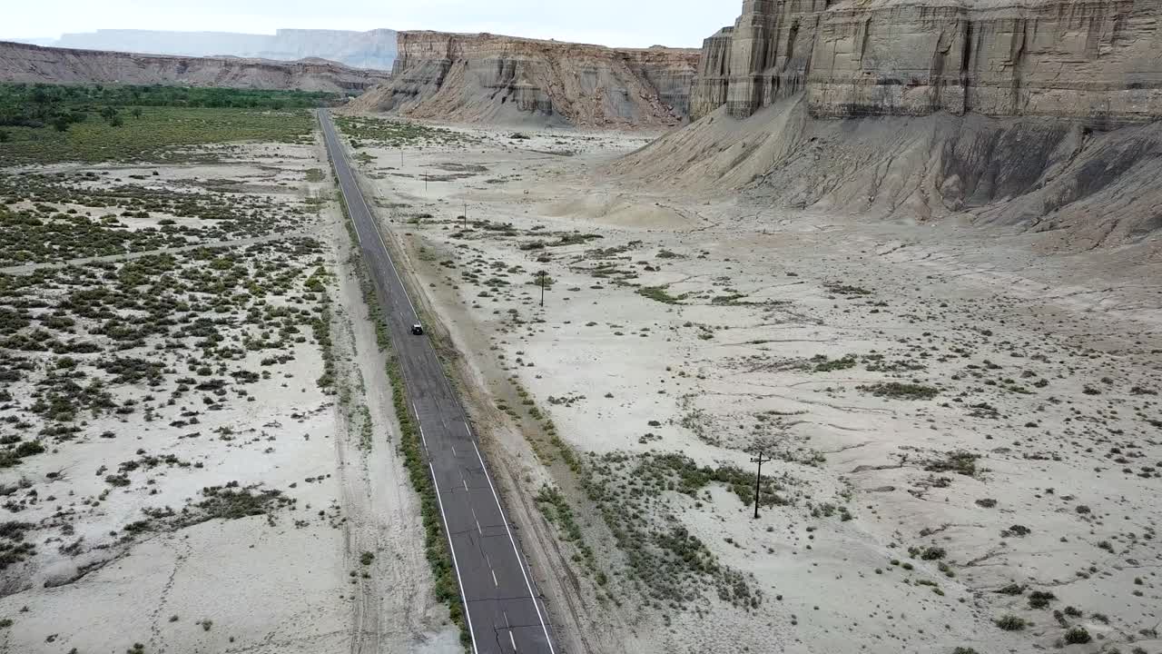 Aerial View of Lonely Car in Desert Road of Utah Landscape Under Factory Butte Rock Formation