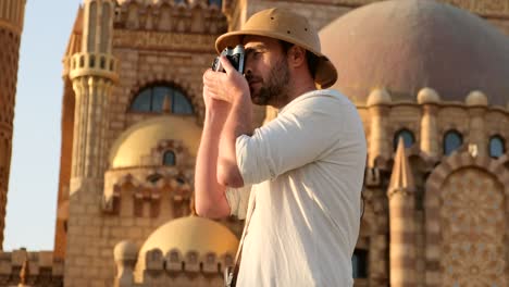 a tourist stands with a camera near the mosque