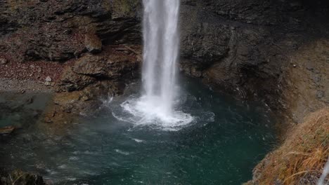 toma en cámara lenta de una cascada en un acantilado rojizo rocoso y agua clara