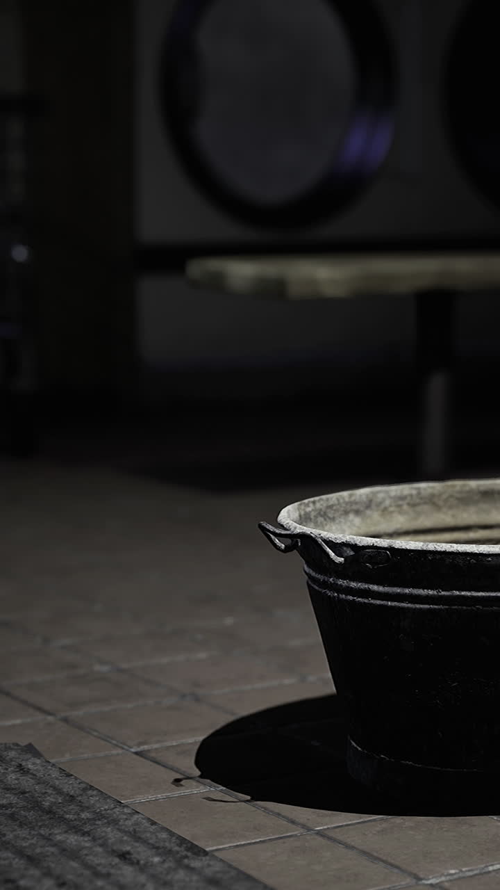 Dark laundry room with a metal basin resting on the floor
