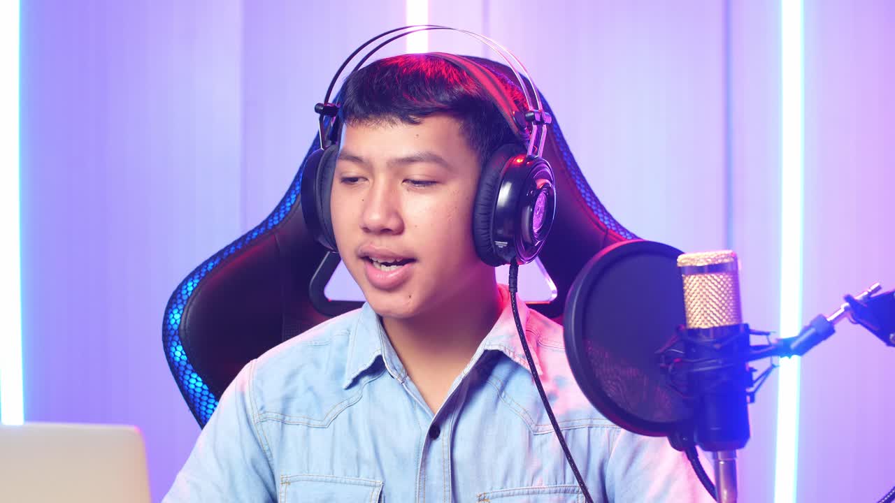 Asian Kid Boy Holding Mobile Phone And Read Comment In Laptop Computer Then Talking To Camera While Live Stream