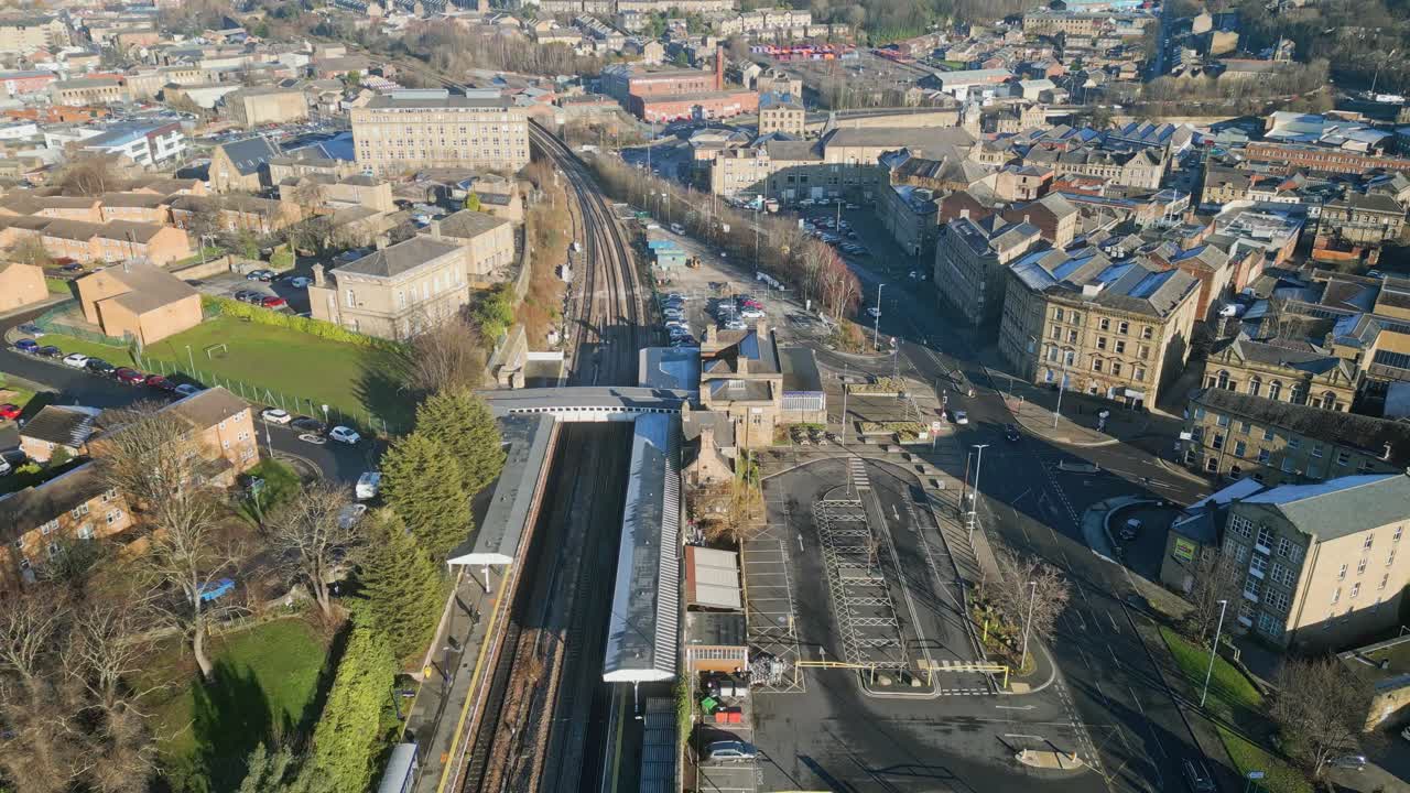 imágenes aéreas cinematográficas de una pequeña ciudad en inglaterra que muestran la estación de tren, el tren y la ciudad ocupada con tráfico y carreteras