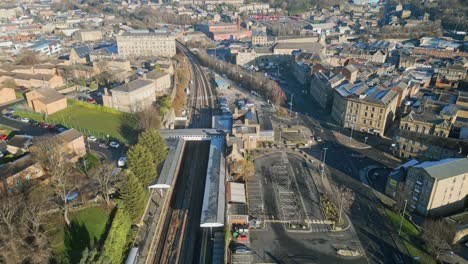 Cinematic-aerial-footage-of-a-small-town-in-England-showing-train-station,-train-and-busy-town-with-traffic-and-roads