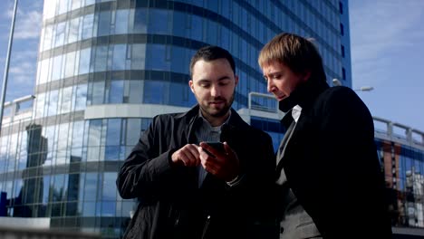 dos jóvenes hombres de negocios que buscan una oferta en su teléfono inteligente