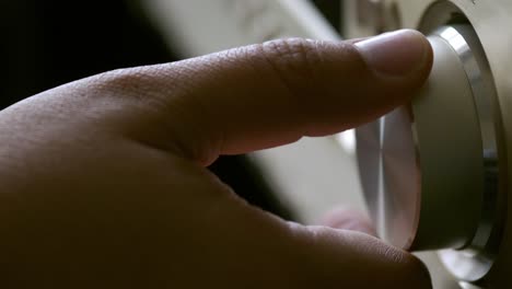 las manos de los hombres ajustan el control de volumen del amplificador del sistema de cine en casa con el botón de ajuste para la radiodifusión y la música