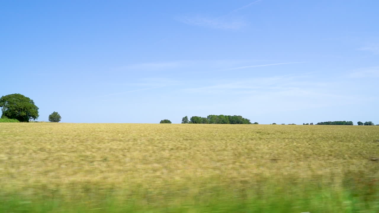 The beautiful green english British countryside passing by out the side of a car driving down the scenic country roads in slow motion showing wheat fields and the farmland of the UK Gloucestershire