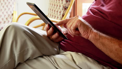 hombre mayor usando una tableta pc mientras está sentado en una silla de balanceo