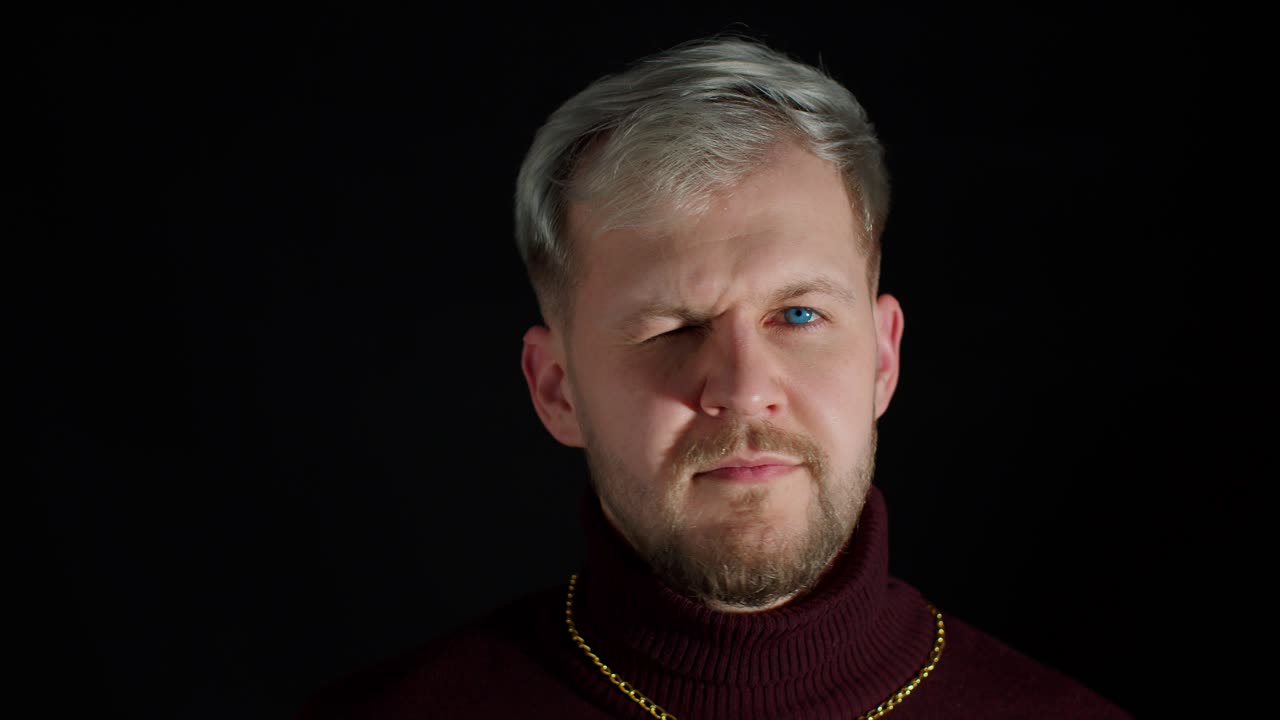 Stylish smiling young man with blue eyes looking at camera, charming smile wink blink eye, flirting