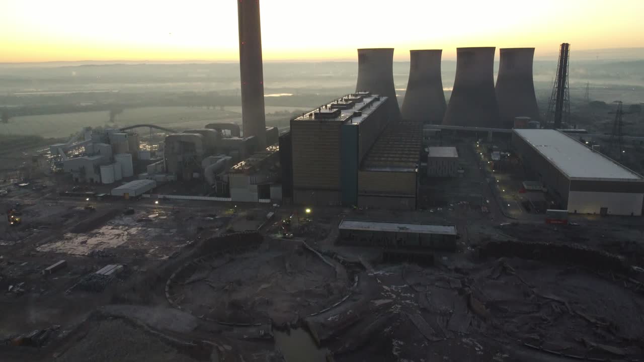 violinistas ferry central eléctrica torres de refrigeración demolición escombros vista aérea se inclina hacia el brillante horizonte del amanecer