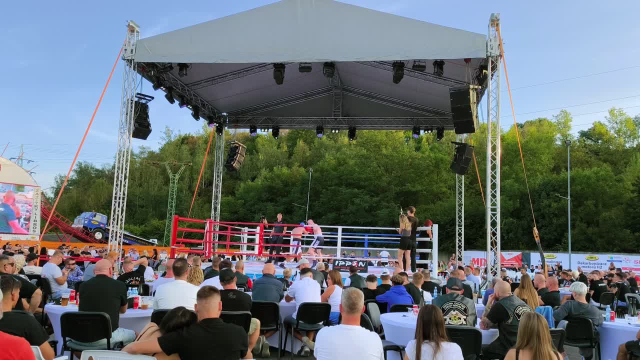 Slow motion clip of outdoor boxing match, people watching the match.
