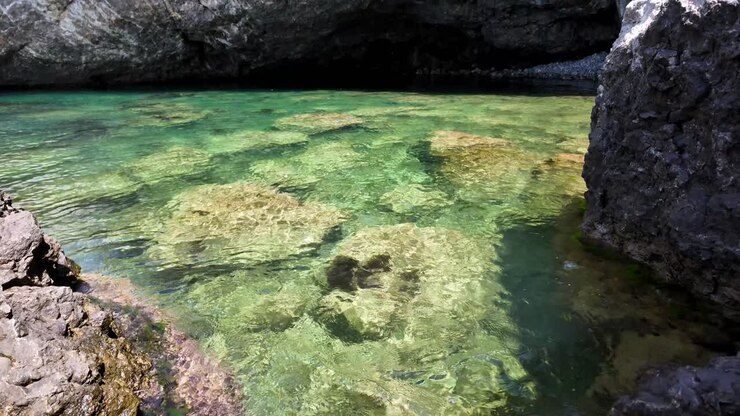 Una vista di una piccola formazione rocciosa con acqua verde limpida, circondata da rocce