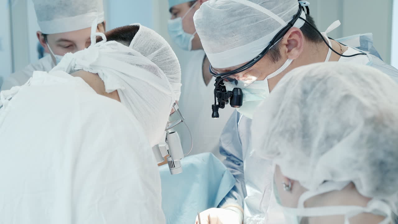구에서 팀으로 일하는 외과 의사: 무정성 유니폼을 입은 경험이 풍부한 의사들이 수술실에서 복잡한 관상동맥 바이파스 수술을 수행합니다.