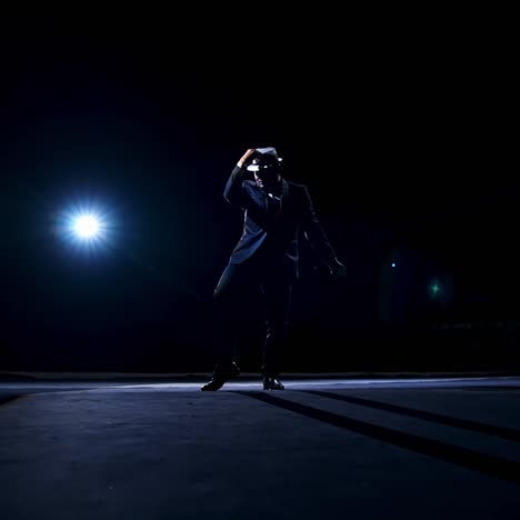 actor performs show with dances on a classic stage. unrecognizible silhouette of a man in classic suit and hat in spot light