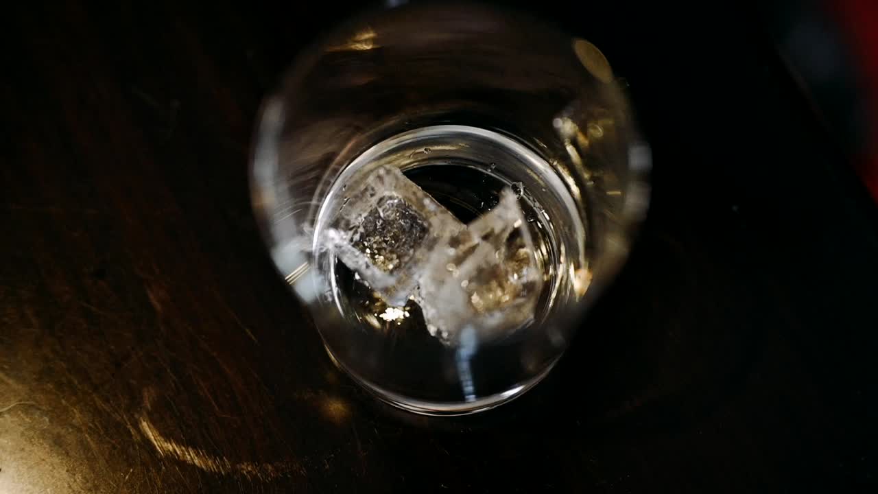 검은색 배경이 있는 유리에 얼음 조각을 떨어뜨리고 위에서 아래로 보기