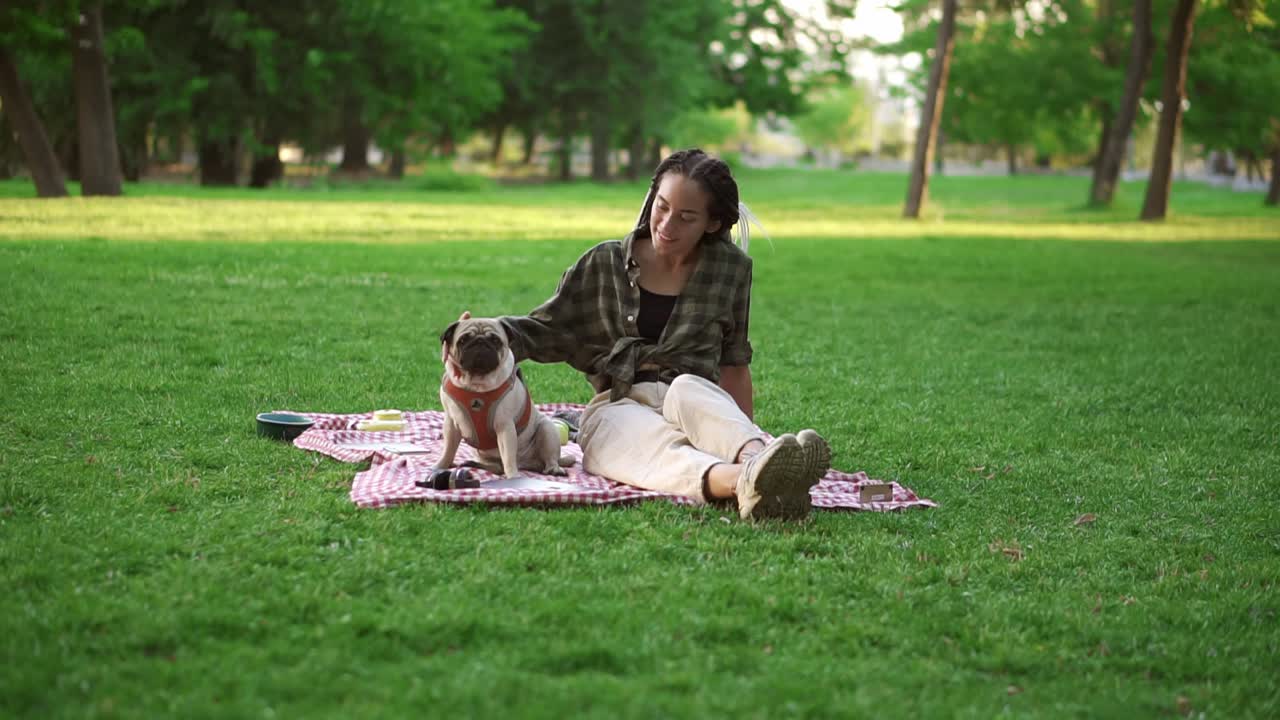 공원에서 잔디 ⁇ 에 앉아 미소 짓는 소녀 전체 강아지 그녀의 앞에 앉아, 그녀는 그를 애정