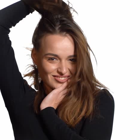 happy brunette moves her hair and looks at camera. attractive young girl on white background. shaking her hair. slow motion.
