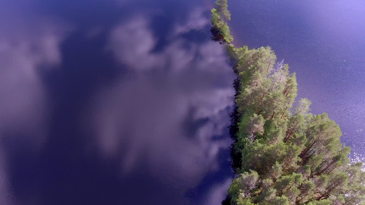 Stunning drone view of a narrow cape in a calm Finnish forest lake
