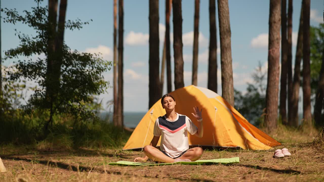 텐트 근처 의 숲 에서 요가 를 연습 하는 여자