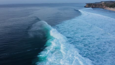 waves and surfers on bali island south coast on indian ocean, cinematic twilight aerial