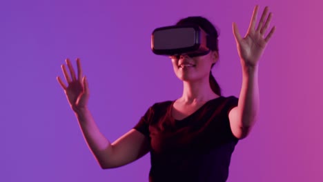 Happy-asian-woman-using-vr-headset-and-touching-virtual-screen-on-purple-background,-slow-motion