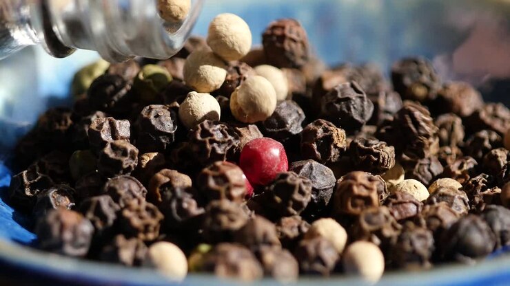 Close-up video of mixed whole spices of white pepper, red pepper and black pepper.