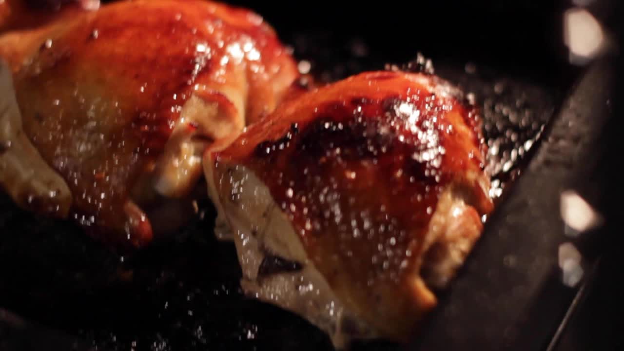 Fresh chicken thighs cooking in a hot oven Handheld shot of preparing dinner