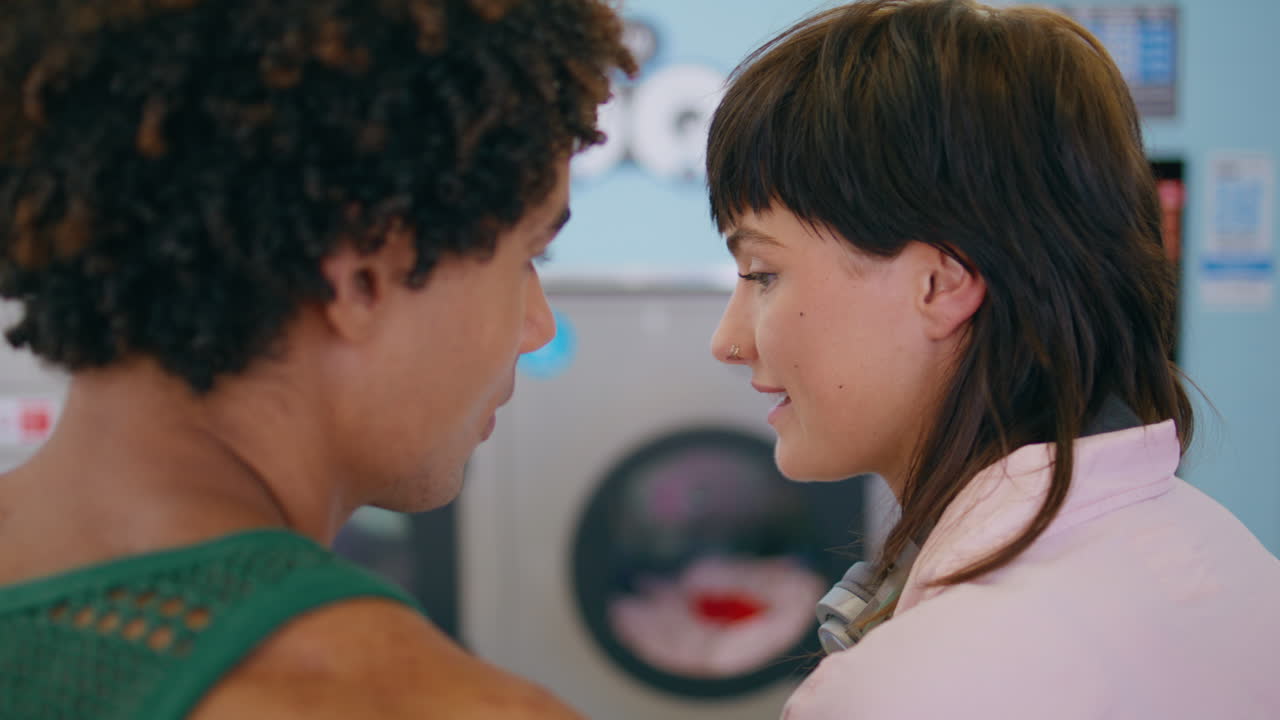 amantes sonrientes en primer plano hablando en una lavandería pública. una pareja afectuosa coqueteando.