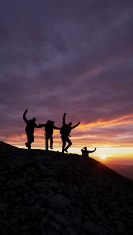 silhouetted hikers ascend a rocky hill at sunset, captured from a low angle