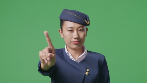 close up of asian woman air hostess pointing at you and disapproving with no index finger sign in the green screen background studio