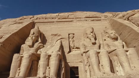 a majestic front view of the great temple at abu simbel, showcasing the colossal seated statues of pharaoh ramesses ii carved into the sandstone cliffs. this unesco world heritage site.