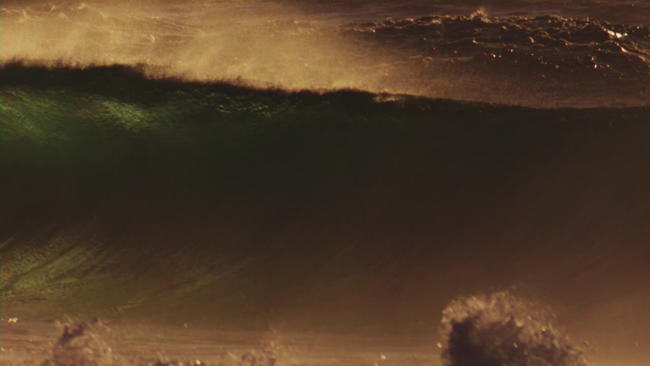 vista de telefoto medio de la suave luz de la madrugada baila a través de las olas como vientos de la costa tiran de la niebla de pulverización del océano por encima