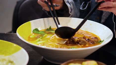 person preparing and eating noodle soup