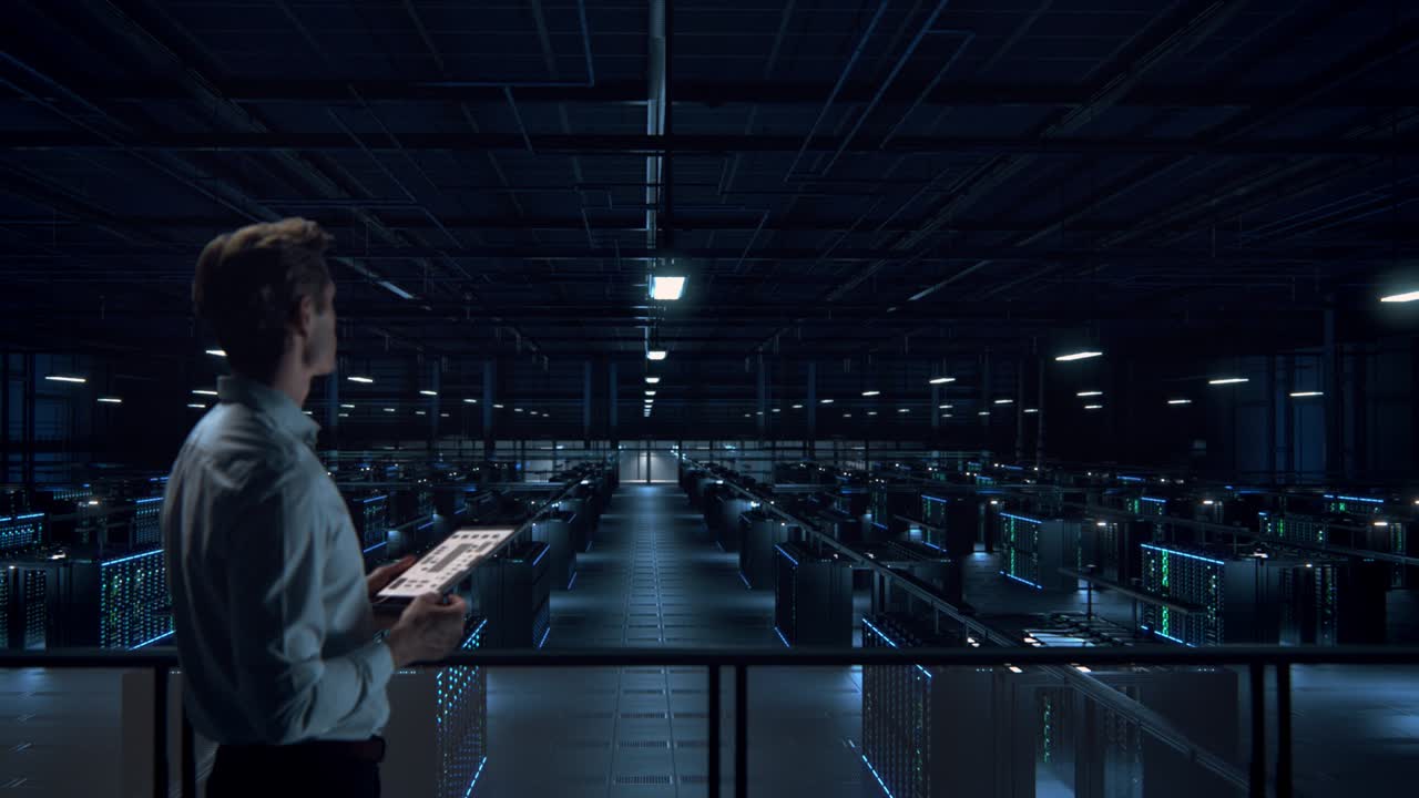 IT Specialist Uses Tablet Computer in Data Center Room. Server Farm Cloud Computing Facility with Maintenance Administrator Working. Cyber Security Engineer Working in Personal Network Protection.