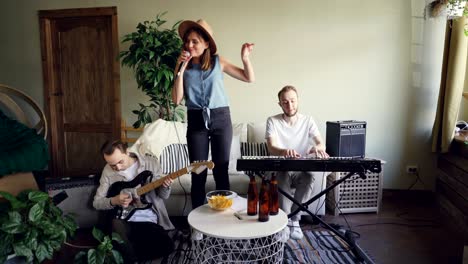 emotional female singer is singing and dancing while guitarist and vocalist are playing musical instruments. happy young people and music concept.