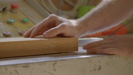 fotografía de cerca de una mano colocada en una tabla de madera en un taller