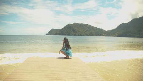 a female model sitting on a jetty located on the caribbean island of trinidad and tobago