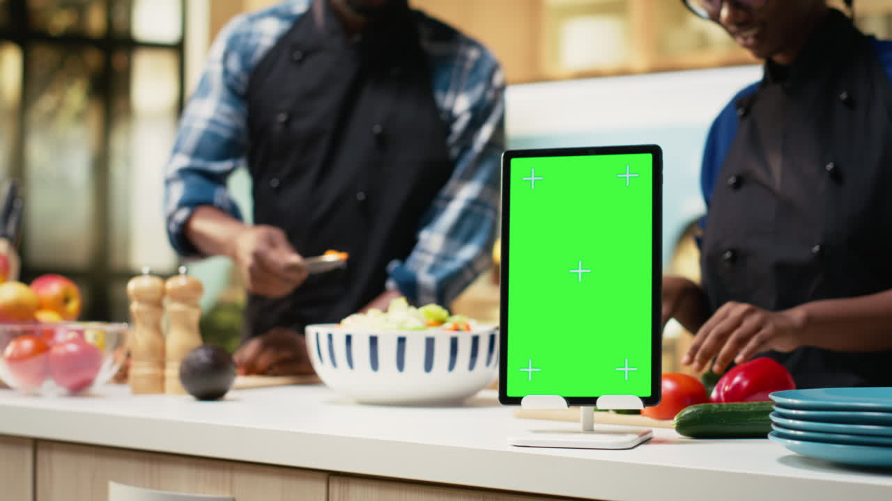 Chefs preparing food in kitchen with tablet