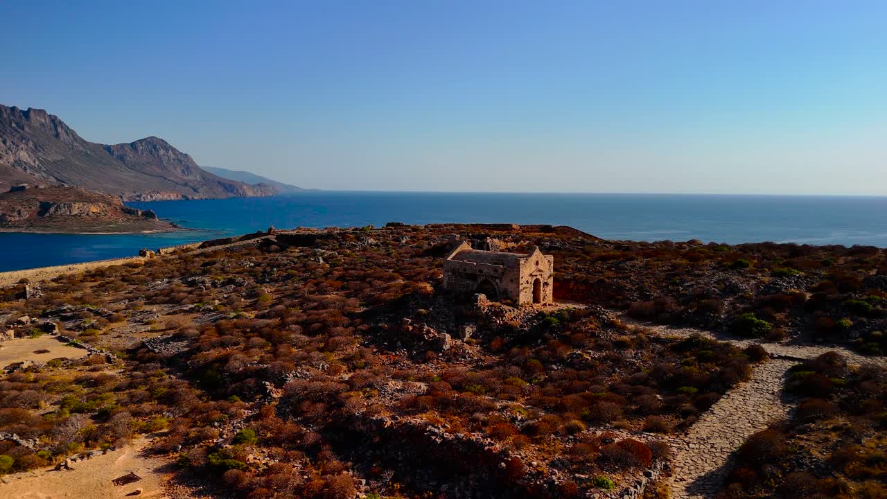 Marvel at the stunning view of ancient ruins overlooking the tranquil sea. The bright afternoon sun highlights the beauty of nature and history intertwined in this picturesque location