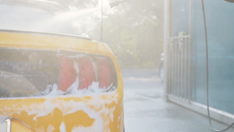 yellow sports car being washed at a car wash