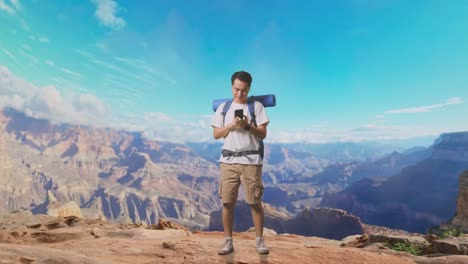 full body of asian male hiker with mountaineering backpack enjoy using smartphone while traveling at the top of mountain