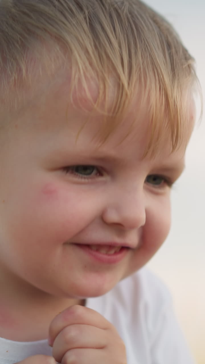 un primer plano de la mano de una mujer ofreciendo una manzana roja a un niño feliz con una camiseta blanca. el niño toma un bocado con entusiasmo, mostrando alegría y deleite en el simple placer de disfrutar de la fruta fresca