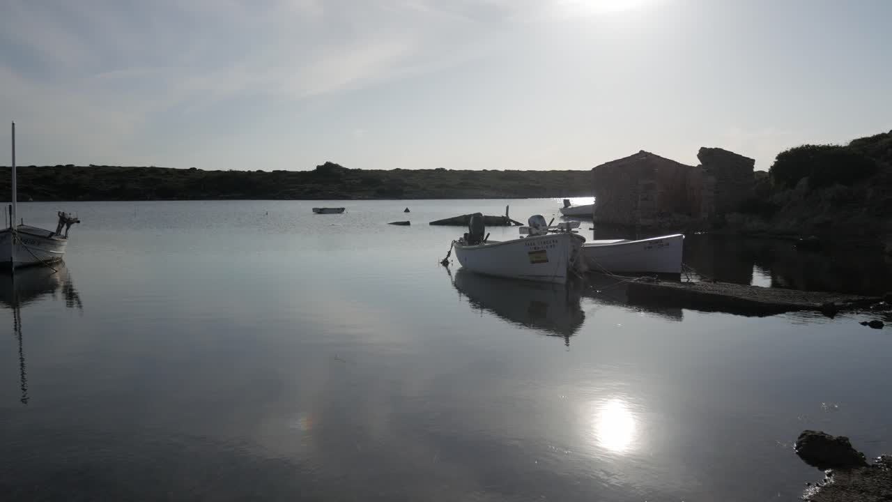 Serene coastal harbor at Puerto De Sanitja with calm water, boats, and rustic buildings