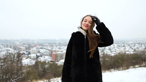 Fröhliches-Weibliches-Model,-Das-An-Einem-Schönen-Wintertag-Auf-Einem-Berg-Vor-Einer-Stadt-Posiert