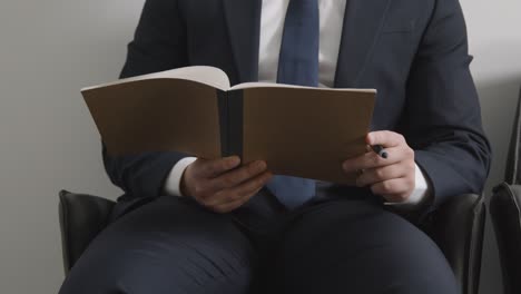 primer plano de un candidato masculino con traje en la oficina revisando notas antes de la entrevista de trabajo